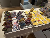 Pokemon producten op drie stellingschappen w.o. verzamelmappen, metalen koffertjes, puzzles, beschermzakjes... onderdeel van combinatiekavel kavels p001 t/m p051 combinatiekavel - afbeelding 4 van  18