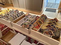 Pokemon producten op drie stellingschappen w.o. verzamelmappen, metalen koffertjes, puzzles, beschermzakjes... onderdeel van combinatiekavel kavels p001 t/m p051 combinatiekavel - afbeelding 9 van  18