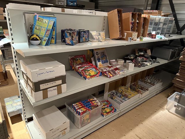 Pokemon producten op drie stellingschappen w.o. verzamelmappen, metalen koffertjes, puzzles, beschermzakjes... onderdeel van combinatiekavel kavels p001 t/m p051 combinatiekavel - afbeelding 1 van  18