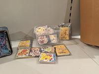 Pokemon producten op drie stellingschappen w.o. verzamelmappen, metalen koffertjes, puzzles, beschermzakjes... onderdeel van combinatiekavel kavels p001 t/m p051 combinatiekavel - afbeelding 15 van  18