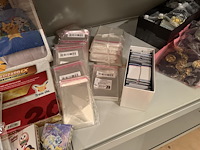 Pokemon producten op drie stellingschappen w.o. verzamelmappen, metalen koffertjes, puzzles, beschermzakjes... onderdeel van combinatiekavel kavels p001 t/m p051 combinatiekavel - afbeelding 17 van  18