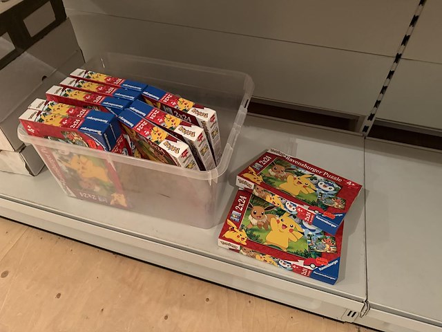 Pokemon producten op drie stellingschappen w.o. verzamelmappen, metalen koffertjes, puzzles, beschermzakjes... onderdeel van combinatiekavel kavels p001 t/m p051 combinatiekavel - afbeelding 18 van  18