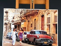Poster van een straat in havana, cuba, met een klassieke rode amerikaanse auto en twee vrouwen op de voorgrond