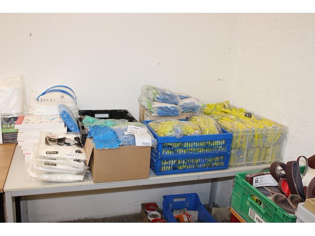 Schoonmaakprodukten w.o. handschoenen, schoenencovers, wegwerpoverals en gezichtskappen op tafel. - afbeelding 1 van  3