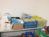 Schoonmaakprodukten w.o. handschoenen, schoenencovers, wegwerpoverals en gezichtskappen op tafel. - afbeelding 1 van  3