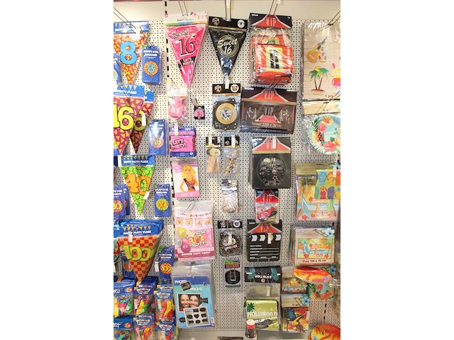 Verjaardags accessoires aan twee en halve wandschappen w.o. slingers, ballonen, tafelkleden en banners. - afbeelding 1 van  3