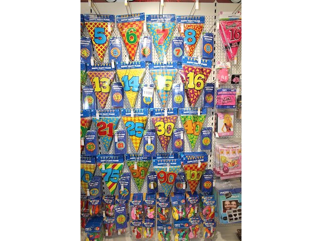 Verjaardags accessoires aan twee en halve wandschappen w.o. slingers, ballonen, tafelkleden en banners. - afbeelding 2 van  3