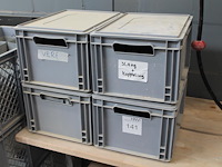 Vijf kunststof kratten met diverse machine onderdelen.