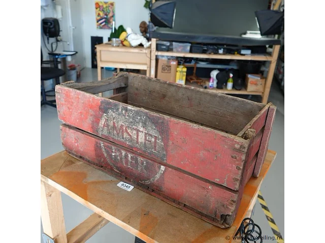 Vintage houten bierkrat van amstel bier met karakteristiek verweerd rood uiterlijk en een rond logo - afbeelding 1 van  7