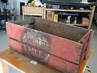 Vintage houten bierkrat van amstel bier met karakteristiek verweerd rood uiterlijk en een rond logo