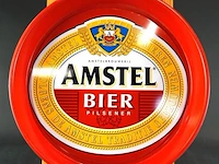 Vintage metalen amstel bier serveerblad met een opvallende rode opstaande rand en het klassieke merklogo
