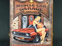 Vintage metalen wandbord met de afbeelding van een klassieke rode muscle car, benzinepompen en een pin-up model